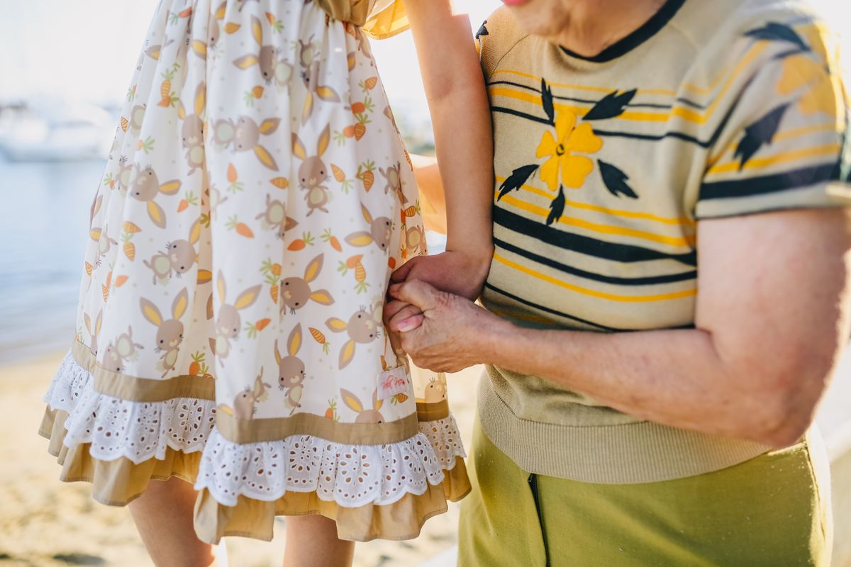 A grandmother and child walking hand in hand on a sunny day